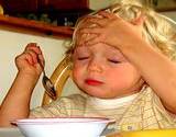 photo of a baby sitting in highchair eating and holding head