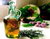 a sprig of rosemary laying next to a glass bottle of olive oil