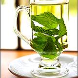 photo of a glass cup full of green tea with a mint leaf