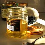 a beautiful photo of an opened jar of honey, a teaspoons with honey and a golden lid laying beside the jar