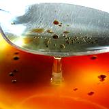 photo of oil and vinegar in a bowl and a teaspoon mixing and dripping