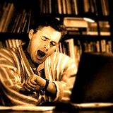 photo of a man sitting at his computer and yawning a sure sign of a sleep disorder