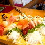 photo of a cutting board with variety of sushi being prepared with rice vinegar