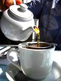 Photo of white tea pot and tea cup with loose tea showing pouring a cup of tea to mix with a hot toddy.