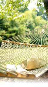 photo of a back yard hammock with straw hat sitting on it