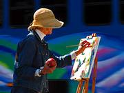 photo of a women painting on canvas outdoors to relieve headache symptoms stress