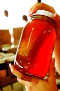 photo of a woman's hands holding a homemade jar of honey with the honeycomb inside